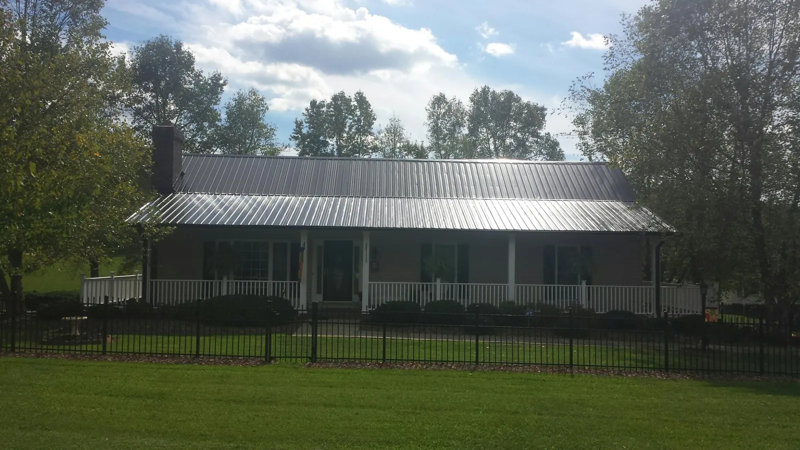 Gray metal roof on a brick ranch with a full width front porch — Gutter Guard Installation work by our crew in Springdale