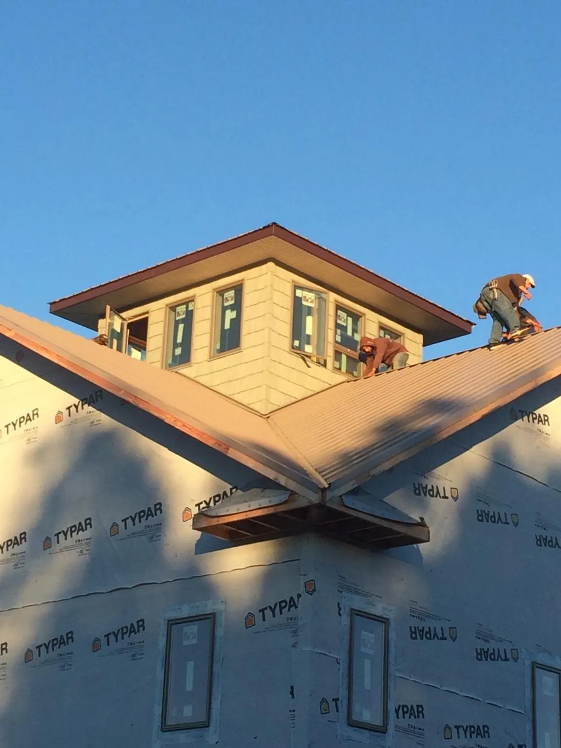 Roofers working around a rooftop cupola on a new metal roof at sunset — Roof Waterproofing in Springdale by Roofing Brothers